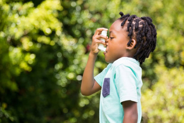 Boy using an asthma inhaler Boy using an asthma inhaler in the park asthma inhaler stock pictures, royalty-free photos & images