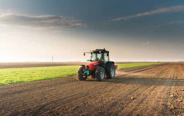 Tractor spreading artificial fertilizers  in field Tractor spreading artificial fertilizers  in field agricultural machinery stock pictures, royalty-free photos & images