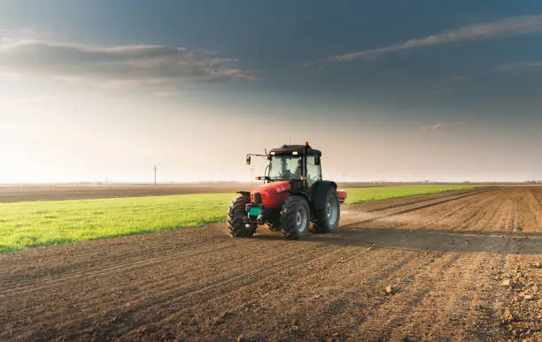 Photo of Tractor spreading artificial fertilizers  in field