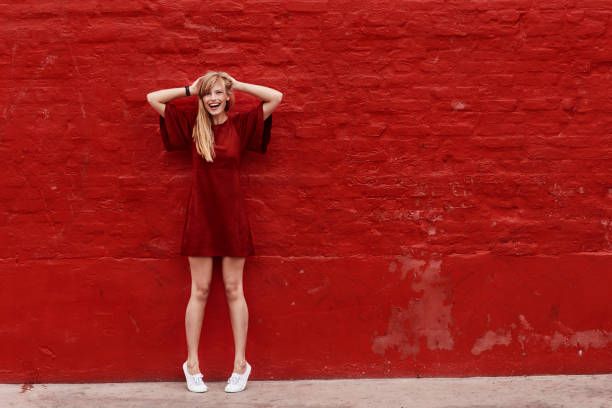 Woman in red Woman in red dress against red wall, portrait blonde model in dress stock pictures, royalty-free photos & images