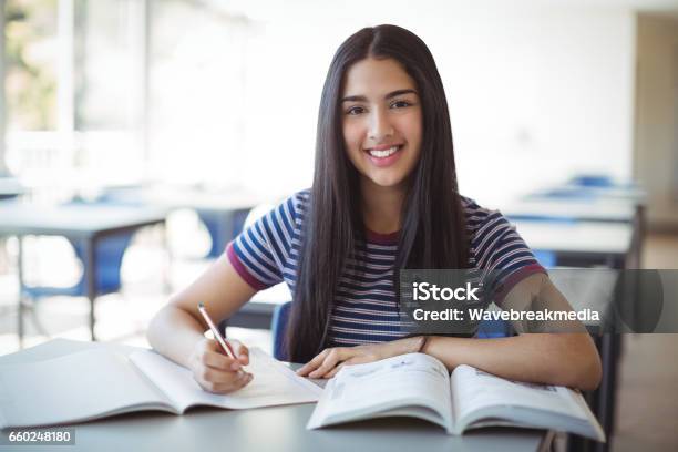 Schoolgirl Doing Homework In Classroom Stock Photo - Download Image Now - Teenager, Writing - Activity, Smiling