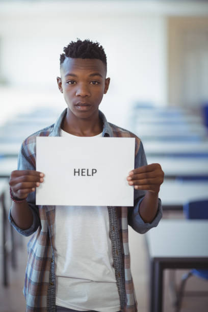 istock Schoolboy holding white paper with text sign in classroom 660249118
