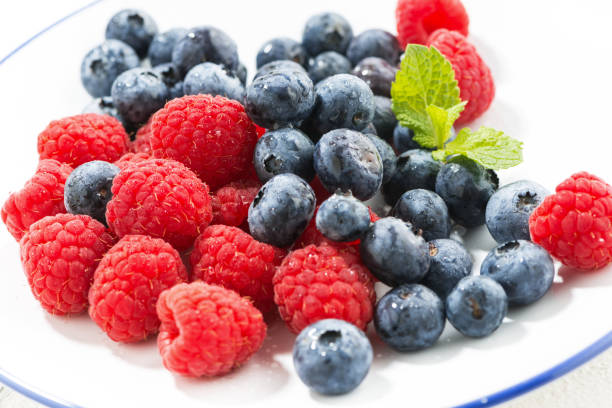 plate with fresh berries on a white background, closeup, horizontal