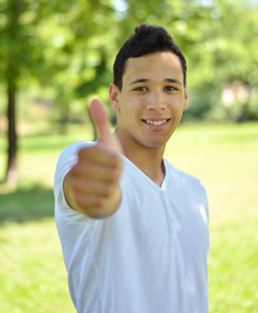 istock Young smiling with thumb up against nature background 660298374