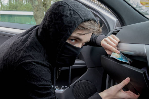 istock Masked teenage criminal stealing from a car 660303330