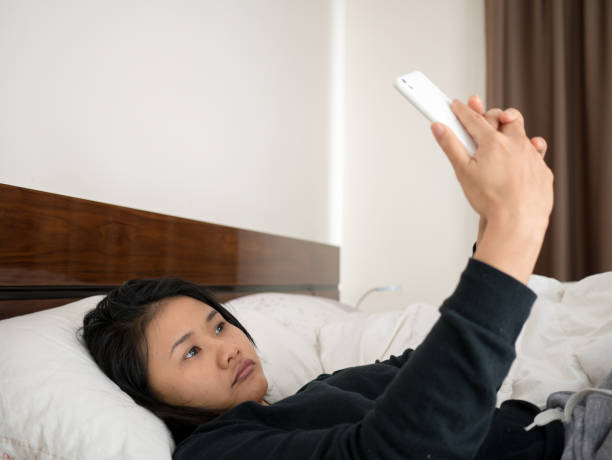 woman lying on bed, addicting to smartphone
