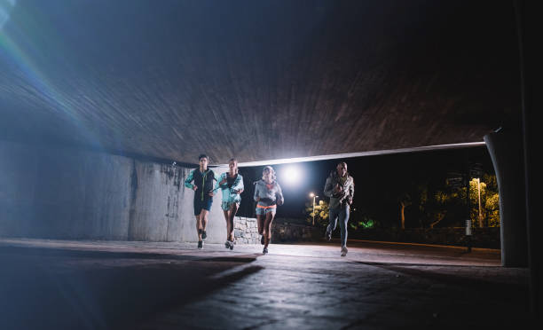 istock Young men and women jogging together at night 660312550