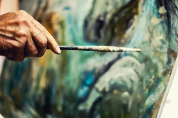 Photo of Portrait of an artist painting on easel. Shot in workshop