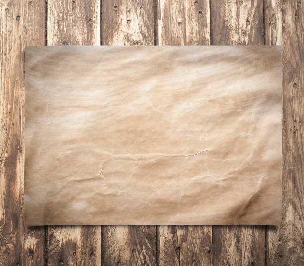 istock Old paper on a brown wooden surface. 660326062