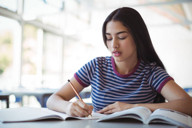 istock Attentive schoolgirl doing homework in classroom 660331008