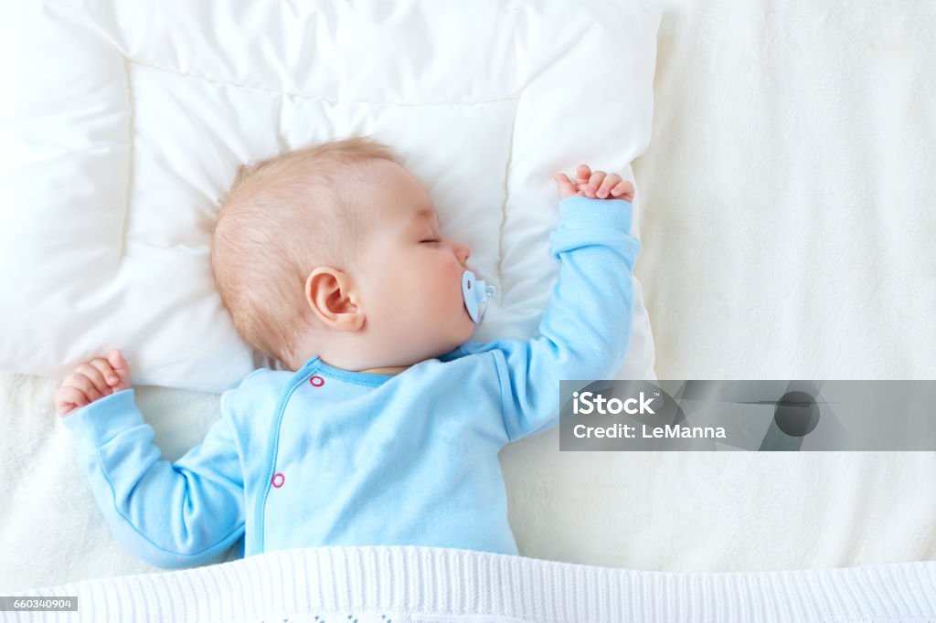 baby sleeping on blue blanket Seven month old baby sleeping on white blanket and pillow. Sleepy child on soft bedding with pacifier Baby - Human Age Stock Photo
