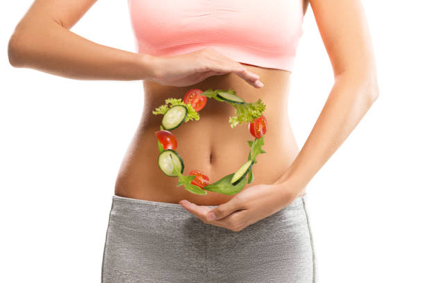 fit, mujer joven sosteniendo un círculo hecho de verduras sobre su abdomen - estreñimiento fotografías e imágenes de stock