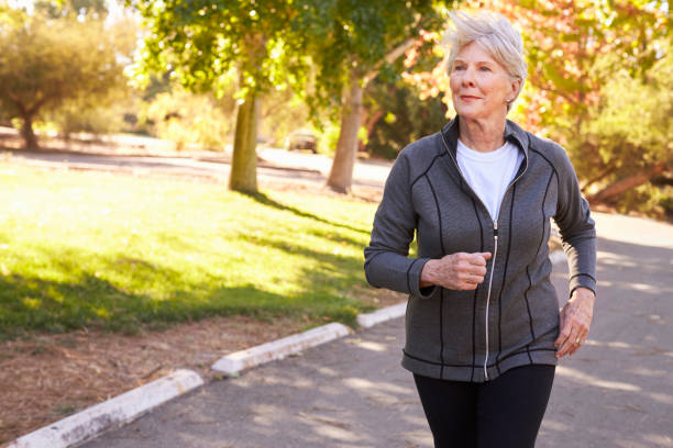 istock Front View Of Senior Woman Jogging Through Park 660353208