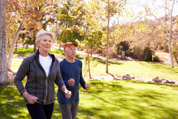 istock Side View Of Senior Couple Power Walking Through Park 660353224