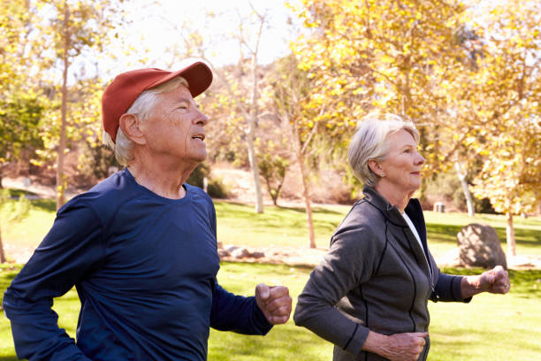 istock Side View Of Senior Couple Power Walking Through Park 660353230
