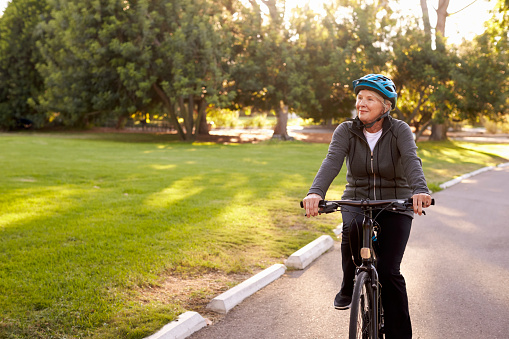 Vista frontal de la mujer mayor en bicicleta a través del parque photo