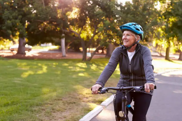 Photo of Front View Of Senior Woman Cycling Through Park