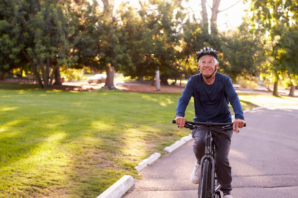 istock Front View Of Senior Man Cycling Through Park 660353306