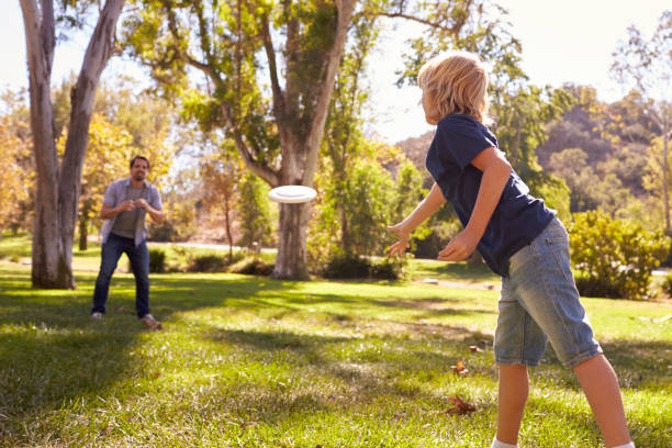 istock Father And Son Throwing Frisbee In Park Together 660353364