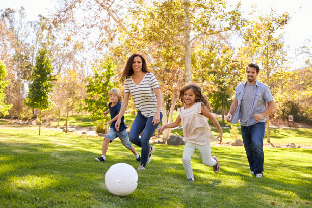 Family Playing Soccer In Park Together