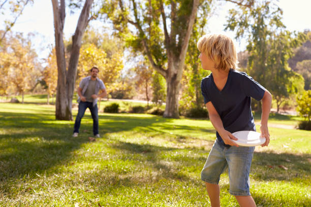 istock Father And Son Throwing Frisbee In Park Together 660353442