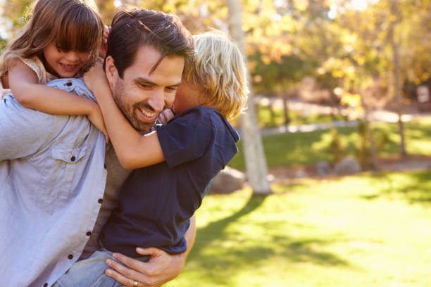istock Father Carrying Son And Daughter As They Play In Park 660353480