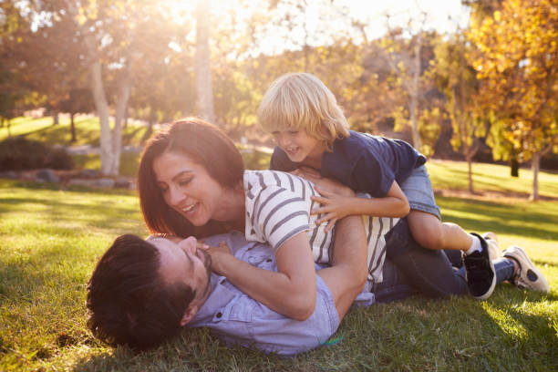 istock Mother And Son Lying On Father In Park 660353526