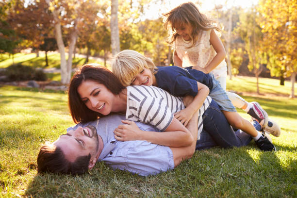 istock Mother And Children Lying On Father In Park 660353538