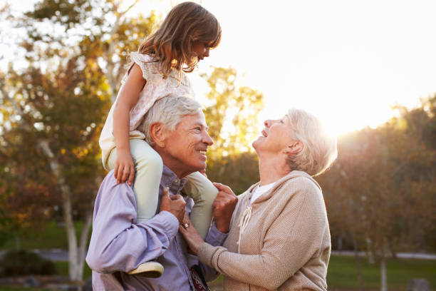 祖父母の孫娘の肩を与える公園に乗る - family grandmother multi generation family nature ストックフォトと画像