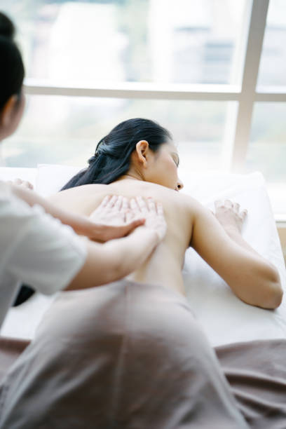 старший массажист делает масляный массаж молодой женщине - thai ethnicity massaging thailand thai culture стоковые фото и изображения