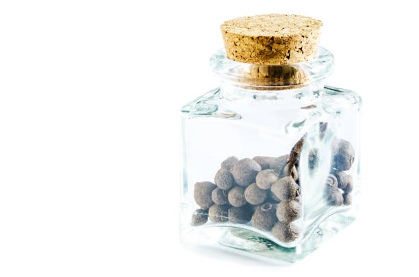 Dry allspice in glass bottle isolated on white background. Closeup macro shot.