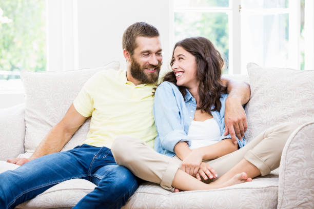 istock Young couple sitting on sofa with arm around 660373632