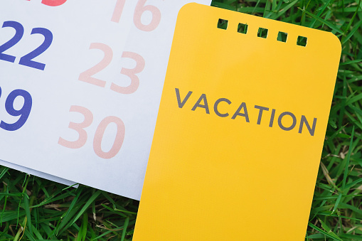 reminder vacation card, notes and calendar with smart phone in green grass background.