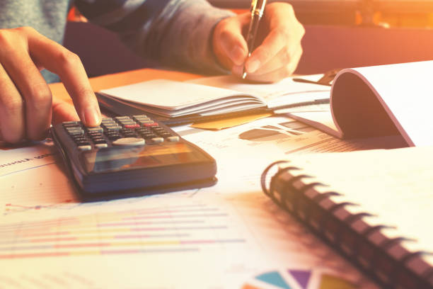 istock calculator with woman hand calculate finance and writing record note. 660384824