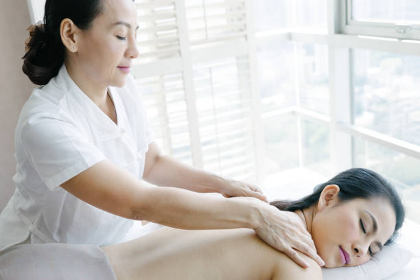 старший массажист делает масляный массаж молодой женщине - thai ethnicity massaging thailand thai culture стоковые фото и изображения