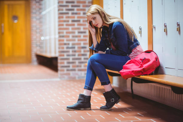 istock Worried student sitting in locker room and looking at the camera 660439142