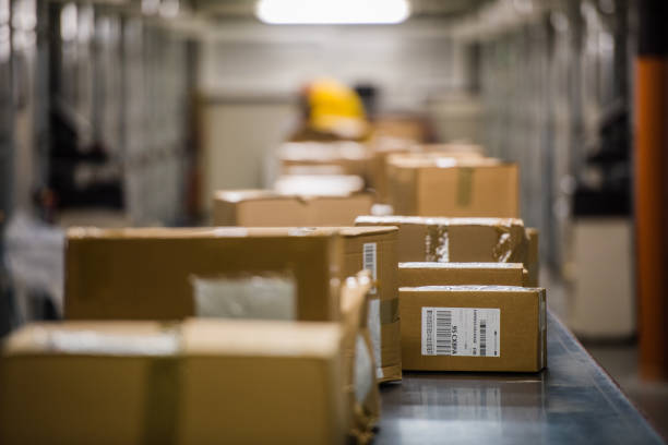 Boxes on conveyer belt Packed boxes moving on conveyer belt in warehouse. conveyor belt stock pictures, royalty-free photos & images