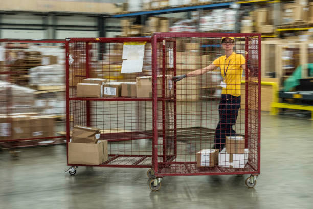 Worker pushing cage trolley Female worker pushing cage trolley loaded with boxes in warehouse. transportation cage stock pictures, royalty-free photos & images
