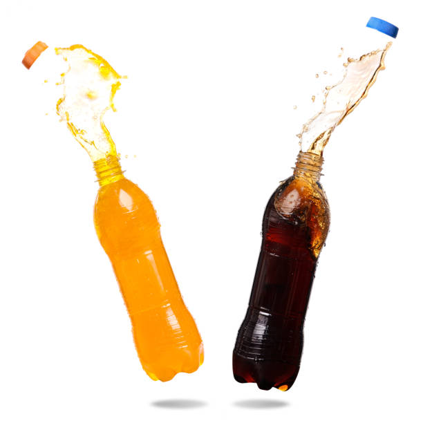 Soft drinks splashing Orange juice and cola splash out of bottle on white background. soda bottle stock pictures, royalty-free photos & images