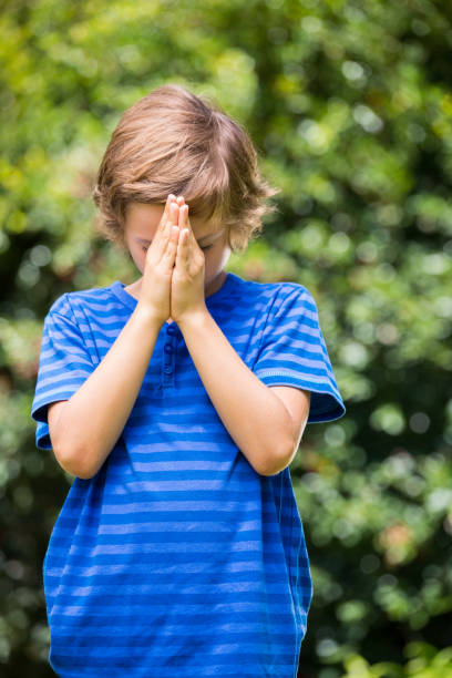 istock Portrait of boy standing and praying 660452698