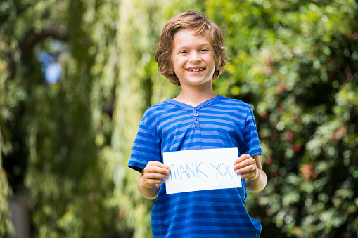 Cute boy smiling and holding a message on a park