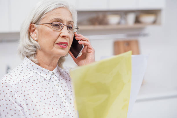 istock Senior housewife talking on mobile phone in kitchen 660469020