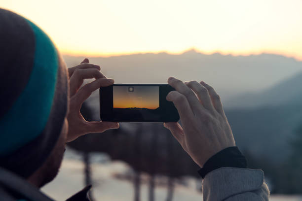istock Man photographing sunset with a smart phone 660482552