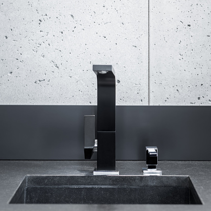Black kitchen worktop, sink with modern tap and grey wall tiles