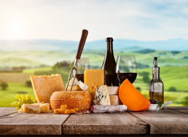 Various kind of cheese served on wooden table. Italian Toscana landscape on background. Traditional pieces of french and italy hand-made cheese. Copyspace for text