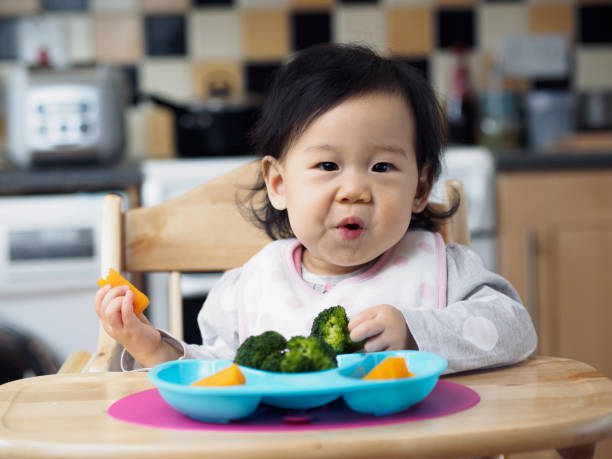 istock baby girl eating vegetable first time 660504184