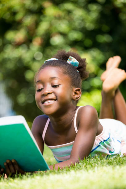 istock Smiling cute mixed-race girl lying and reading a book 660507180