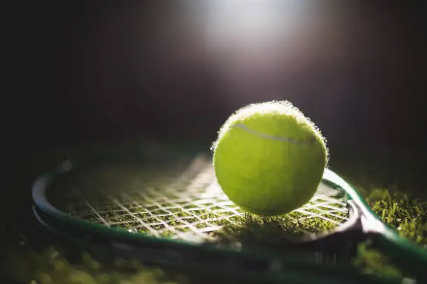 Close up of tennis ball with racket on grass