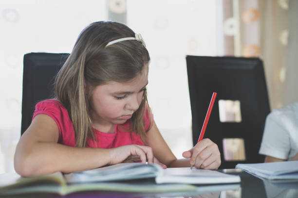 istock Beautiful schoolgirl doing homework at home 660517262