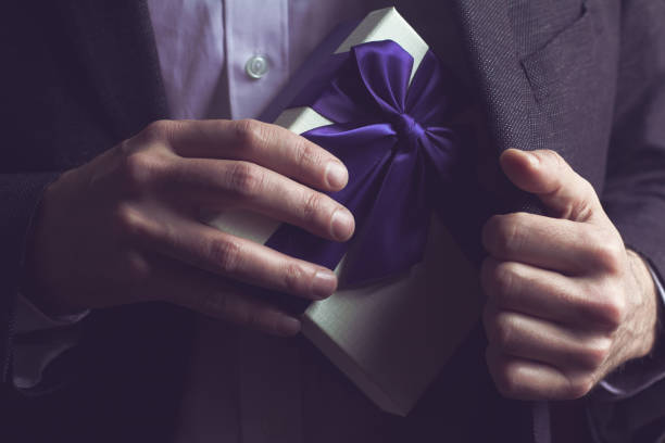 istock Man in suit opening a gift with purple ribbon 660530406